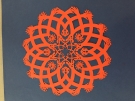 an intricate orange paper craft decoration created by Allan Troxler ’69 
